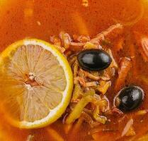 Solyanka mix soup with sausages, olives and lemon photo