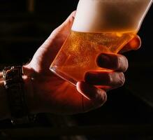 Close-up of barman hand at beer tap pouring a draught lager beer photo