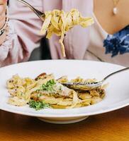 Woman Eating pasta with Mushrooms on wood table photo