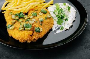 Delicious wiener hunter schnitzel with sauce and french fries close-up on a plate photo