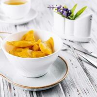 Yellow dumplings with sour cream on a plate closeup photo