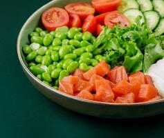 Poke bowl with salmon, cucumber, tomato, rice and edamame beans photo