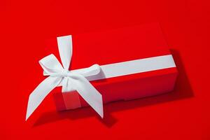 Red gift box with white ribbon isolated on yellow photo