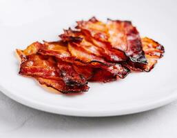 Plate with tasty bacon slices on stone photo