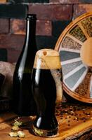 Glass of dark beer and bottle on wooden photo