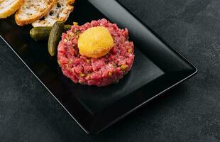 Beef tartar with salted cucumbers and grilled bread photo