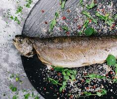 Grilled spicy fish on black plate, top view photo