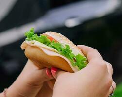 woman eating burger sandwich at outdoor terrace bistro photo