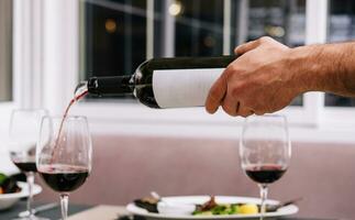 Waiter pouring red wine into wineglass photo