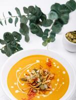 Hokkaido or butternut pumpkin soup with curry and seeds photo