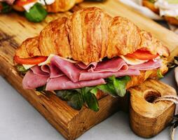 Delicious croissant sandwich on wooden board photo