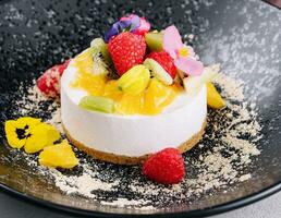 Round cheesecake with fruit decoration and cup of coffee photo