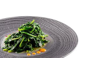 Fried spinach on black plate isolated photo