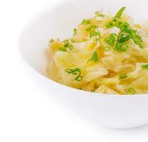 Bowl of tasty fermented cabbage on white photo