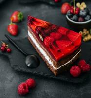 Sweet cake with fresh berries and jelly on old stone board photo