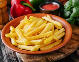 Fresh tasty french fries and red sauce on a wooden cutting board photo