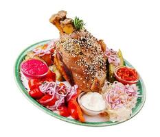 Tasty pork knuckle with sauces and vegetables photo