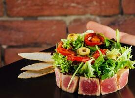 tuna tartare served with toast and salad on black stone plate photo