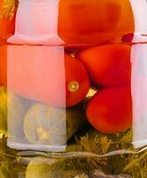 salado pepinos y Tomates en un vaso tarro foto