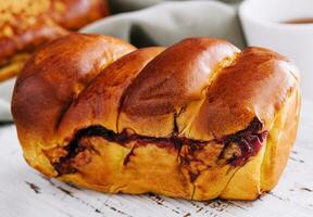 Delicious baked bun with cherry on white wood photo