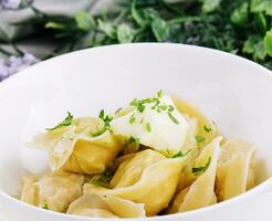 Delicious cooked dumplings with sour cream photo