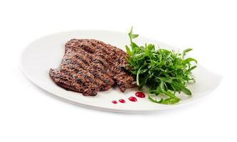 Ribeye steak with arugula on white plate photo