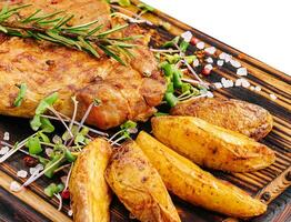 Grilled steak with baked potatoes on wood photo