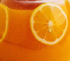 Orange tea in a jug with orange pieces photo