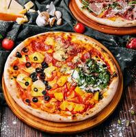 Tasty assorted pizzas on a wooden background photo