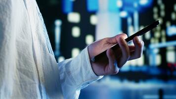 Man strolling around cityscape at night, using smartphone to buy stuff online. Carefree person enjoying wandering in empty metropolitan landscape, using cellphone, close up photo