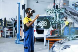 African american mechanic in repair shop using AR holograms to check car performance parameters during maintenance. Certified garage employee using futuristic vr headset to examine damaged vehicle photo