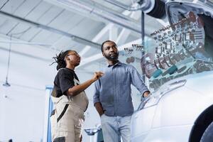 Specialist in repair shop using AR technology to show man defective car pistons. Garage worker using futuristic vr headset to inform client of what dangers his vehicle is facing if left unfixed photo