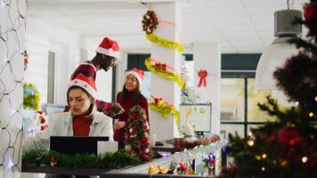 Focused employee in Christmas decorated office working on overdue project while carefree coworkers have fun together looking at decorations. Stressed worker in xmas adorn workspace photo