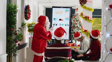 experimentado altavoz vestido como Papa Noel claus haciendo presentación en frente de empresa trabajadores utilizando caramelo caña puntero. empleados aprendizaje cómo a avanzar su carrera durante Navidad negocio reunión foto