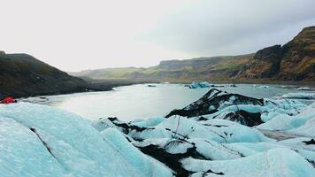 Icelandic vatnajokull glacier lagoon with massive blocks of ice in covered frost arctic landscapes, frozen diamond icebergs near snowy mountains. Icy polar national landmark. Handheld shot. photo