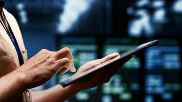 IT admin evaluating energy efficient server clusters using renewable sources to reduce electronics carbon footprint. Engineer typing on tablet in sustainable high tech facility, close up photo