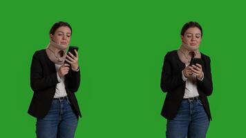 Close up of person with cervical collar texting messages on mobile phone, standing over full body green screen. Female manager browsing internet website ansd wearing medical neck brace. photo