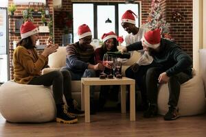 Cheerful young company workers pouring sparkling wine into glasses and toasting to new year holiday. Happy men and women coworkers drinking alcohol beverage while celebrating christmas in office photo