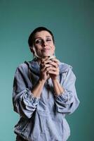 Portrait of happy woman enjoying cup of coffee holding mug with hot beverage drinking during work break in studio. Brunette model with short hair having satisfied expression after testing the drink photo