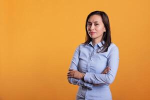 Happy model standing with arm crossed in studio over yellow background, being confident and carefree on camera. Cheerful filipino young adult with natural expression having fun, enjoying free time photo