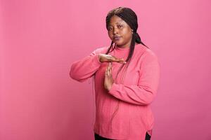 Displeased angry woman doing timeout and break gesture while making disapproval expression in studio, expressing t shape sign with hands. Serious young adult advertising refuse in studio photo