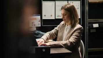 Private detective prepares to depart office, arranging laptop bag and papers for investigation. Female agent packing files after investigative detective work, stands and walks out of evidence room. photo