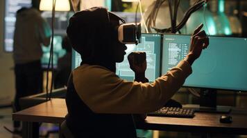 Cyber criminal using virtual reality haeadset to hack computer firewall, creating system malware and security breach to steal government information. Young spy doing hacktivism. Handheld shot. photo
