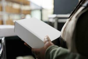 Storage room worker holding white cardboard boxes, checking products before shipping packages in warehouse. Stockroom supervisor working at customers orders during merchandise inventory photo