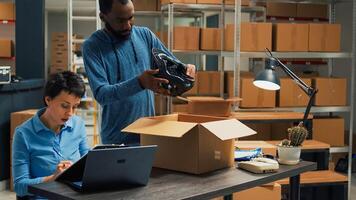 Young entrepreneurs working on goods shipment in warehouse space, putting merchandise from racks in cardboard boxes. Team of partners using products to work on startup development. photo