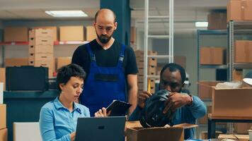 Diverse people shipping products from warehouse stock and packing merchandise in boxes. Entrepreneurs working on small business development and goods shipment, startup. Handheld shot. photo