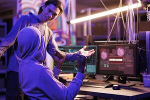 Smiling criminals hacking database and showing victory gesture after successful breach. Happy young hackers celebrating breaking into website and passing cybersecurity system photo