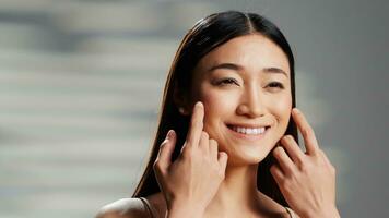 positivo modelo con luminoso piel creando belleza anuncio, con productos cosméticos para brillante radiante apariencia. asiático mujer posando en estudio y publicidad cuerpo positividad Campaña en cámara. foto