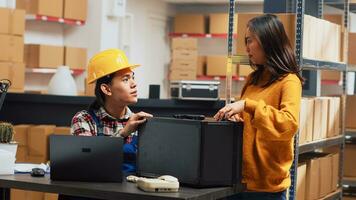 asiático adulto comprobación deposito productos desde bastidores, utilizando almacén valores producción a trabajo en logística en ordenador personal. joven empleado planificación orden distribución para negocio plan a oficina. Mano disparo. foto