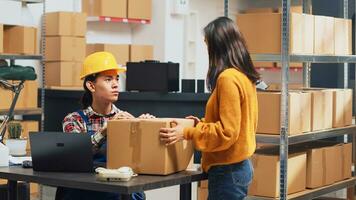 Team of people doing quality control in warehouse, checking stock production before sending retail order packages. Young employees doing teamwork in storage room for management. Handheld shot. photo